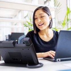 Digital_Workplaces_Importance A woman using Crestron Flex video conferencing system in a modern office setting.