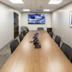 0T1A6967 Modern conference room with large table and video display for meetings.